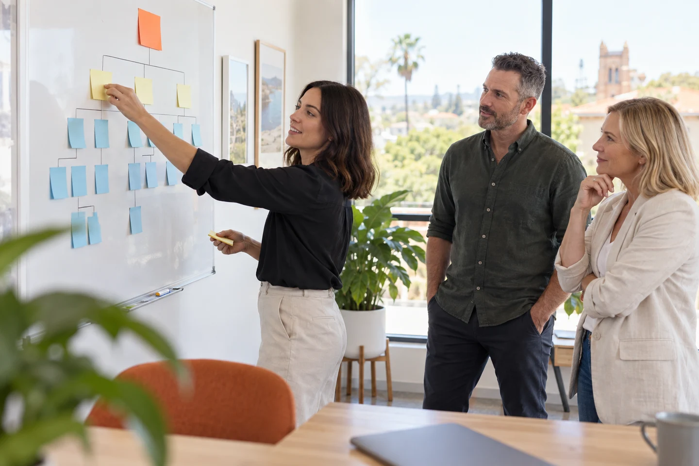 AI-generated photo showing A web strategist arranging sticky notes into a site map on a whiteboard in a Norwood office while two business owners watch