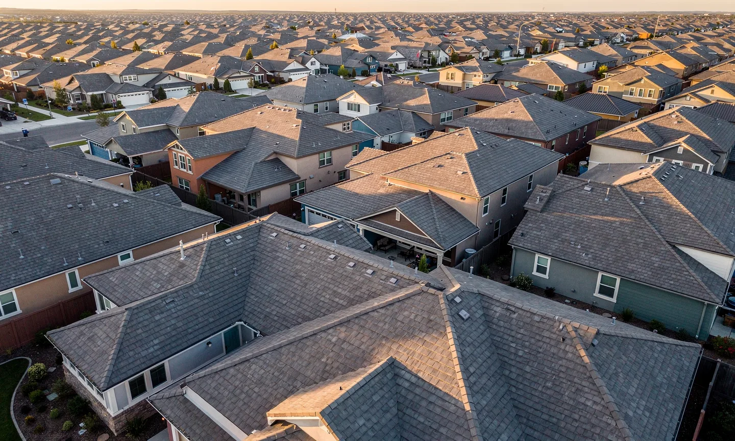 Aerial view of a suburban neighbourhood of shingle rooftops at golden hour